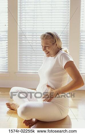 Pregnant woman sitting on the floor touching her abdomen View Large Photo Image Stock Image - Pregnant woman sitting on the floor touching her abdomen. Fotosearch
