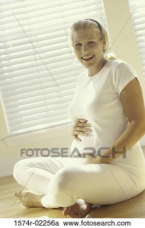 Pregnant woman sitting on the floor touching her abdomen View Large Photo Image Stock Image - Pregnant woman sitting on the floor touching her abdomen. Fotosearch