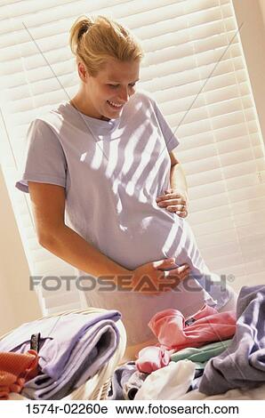 Stock Image - Pregnant woman touching her abdomen. Fotosearch