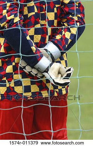 Stock Photo - Rear view of a goalie seen through a net. Fotosearch