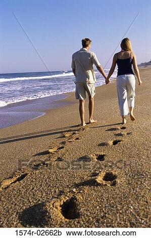 Rear view of a young couple walking on the beach View Large Photo Image Stock Image - Rear view of a young couple walking on the beach. Fotosearch