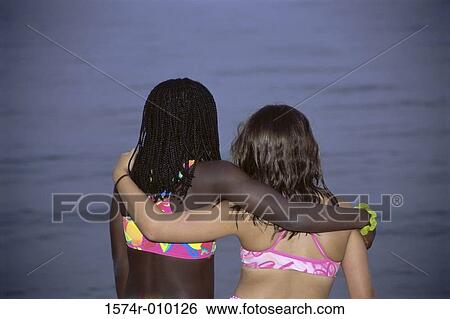 Rear view of two girls together on the beach View Large Photo Image Stock Photograph - Rear view of two girls together on the beach. Fotosearch
