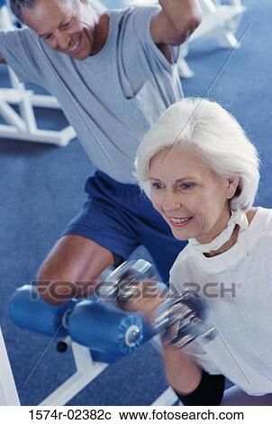 Stock Image - Senior couple exercising in a health club. Fotosearch