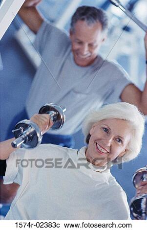 Stock Image - Senior couple exercising in a health club. Fotosearch