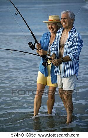 Stock Image - Senior couple fishing at the beach. Fotosearch