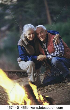 Senior couple kneeling in front of a camp fire View Large Photo Image Stock Image - Senior couple kneeling in front of a camp fire. Fotosearch