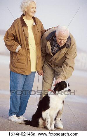 Senior couple standing with their dog on the beach View Large Photo Image Stock Image - Senior couple standing with their dog on the beach. Fotosearch