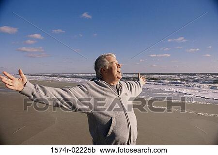 Stock Image - Senior man exercising on the beach. Fotosearch