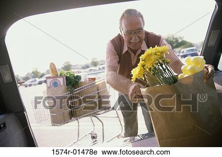 Stock Image - Senior man putting shopping bags into his car. Fotosearch