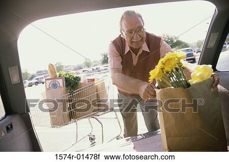 Stock Image - Senior man putting shopping bags into his car. Fotosearch