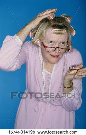 Stock Image - Senior woman putting curlers in her hair. Fotosearch