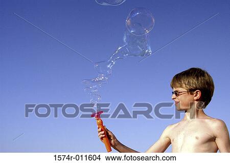 Picture - Side profile of a boy blowing bubbles. Fotosearch