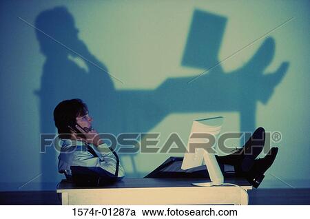 Stock Image - Side profile of a businessman talking on a telephone. Fotosearch