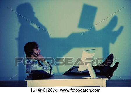 Stock Image - Side profile of a businessman talking on a telephone. Fotosearch
