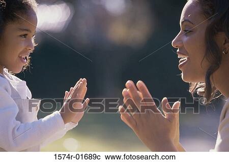 Side profile of a mother playing pattycake with her daughter View Large Photo Image Stock Image - Side profile of a mother playing pattycake with her daughter. Fotosearch