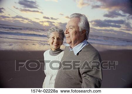Stock Image - Side profile of a senior couple standing on the beach. Fotosearch