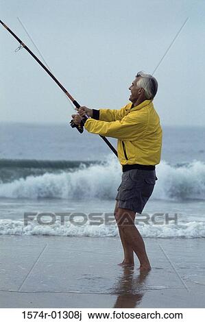 Stock Image - Side profile of a senior man fishing at the beach. Fotosearch