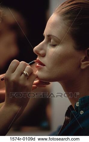 Stock Image - Side profile of a young woman applying lip liner. Fotosearch