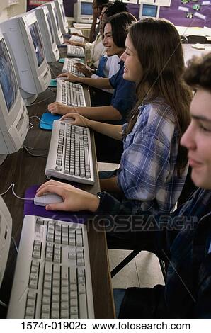 Stock Image - Side profile of group of teenage students using computers in a classroom. Fotosearch