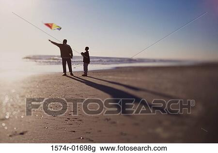 Silhouette of a father and son flying a kite on the beach View Large Photo Image Stock Image - Silhouette of a father and son flying a kite on the beach. Fotosearch