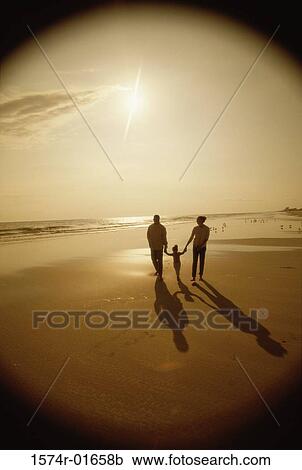Silhouette of parents walking on the beach with their child View Large Photo Image Stock Image - Silhouette of parents walking on the beach with their child. Fotosearch