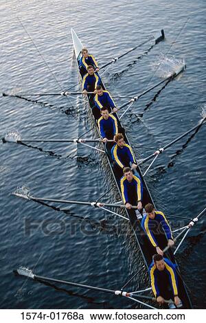Stock Image - Team of young men rowing a boat. Fotosearch