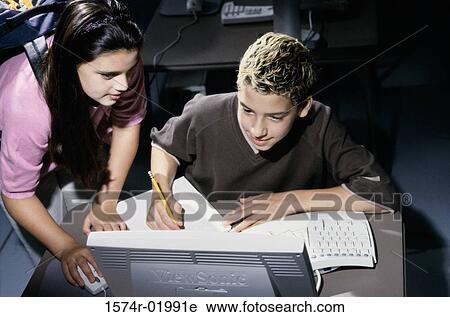 Stock Image - Teenage boy and a teenage girl in front of a computer monitor. Fotosearch
