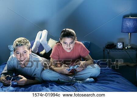 Stock Image - Teenage boy and a teenage girl playing video games. Fotosearch