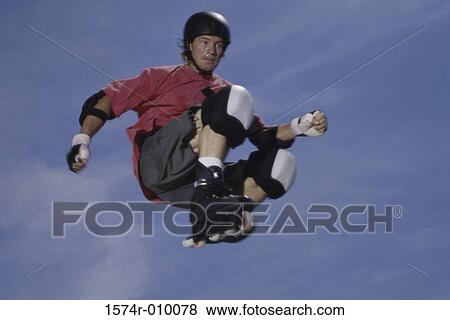 Stock Photo - Teenage boy jumping in mid air wearing inline skates. Fotosearch