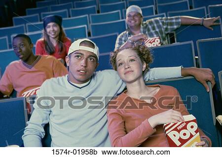Stock Image - Teenage girl and a young man watching a movie in a movie theater. Fotosearch