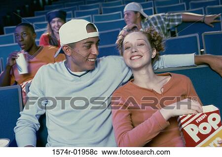 Teenage girl and a young man watching a movie in a movie theater View Large Photo Image Stock Image - Teenage girl and a young man watching a movie in a movie theater. Fotosearch