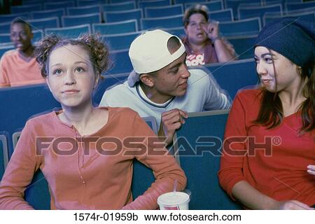 Stock Image - Teenage girl and a young man watching a movie in a movie theater. Fotosearch