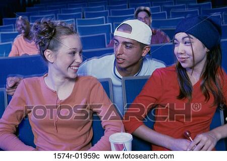 Stock Image - Teenage girl and a young man watching a movie in a movie theater. Fotosearch