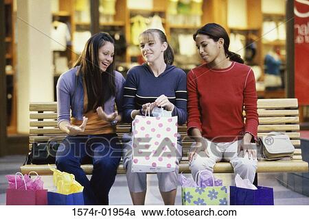 Stock Image - Three teenage girls with shopping bags. Fotosearch