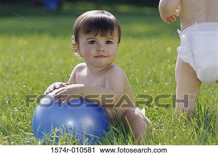 Two baby girls playing on a lawn View Large Photo Image Stock Image - Two baby girls playing on a lawn. Fotosearch