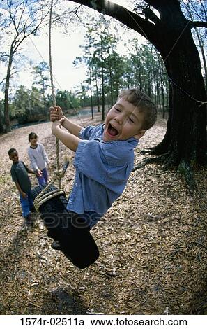 Two boys and a girl playing on a tire swing View Large Photo Image Stock Image - Two boys and a girl playing on a tire swing. Fotosearch