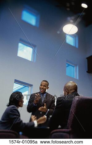 Stock Image - Two businessmen and a businesswoman in a meeting. Fotosearch