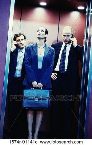Stock Image - Two businessmen and a businesswoman in an elevator. Fotosearch