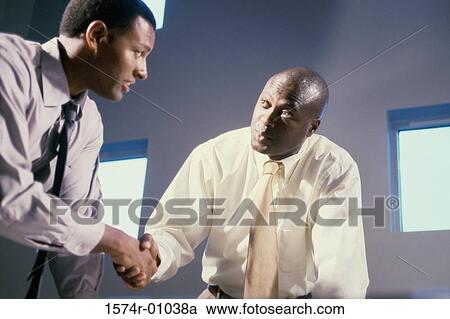 Two businessmen shaking hands in an office View Large Photo Image Stock Image - Two businessmen shaking hands in an office. Fotosearch