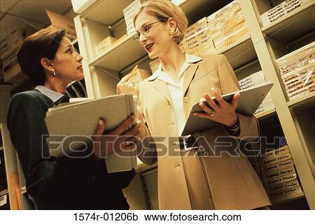 Stock Image - Two businesswomen holding files. Fotosearch