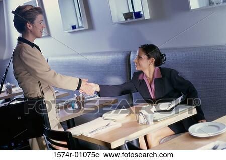 Two businesswomen shaking hands in restaurant View Large Photo Image Stock Image - Two businesswomen shaking hands in restaurant. Fotosearch