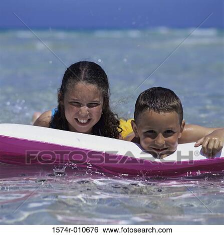 Two children floating on an inflatable raft View Large Photo Image Stock Photograph - Two children floating on an inflatable raft. Fotosearch