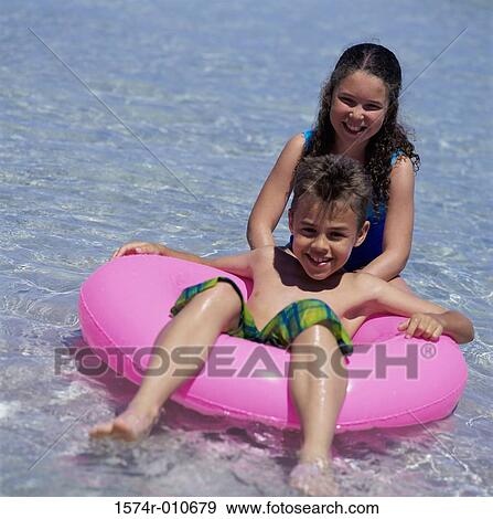 Two children with an inflatable ring at the beach View Large Photo Image Stock Photo - Two children with an inflatable ring at the beach. Fotosearch