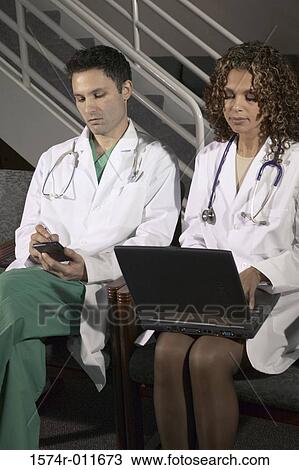 Two doctors sitting together View Large Photo Image Stock Image - Two doctors sitting together. Fotosearch