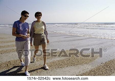 Two mid adult women walking on the beach View Large Photo Image Stock Image - Two mid adult women walking on the beach. Fotosearch