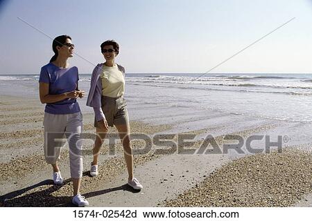 Two mid adult women walking on the beach View Large Photo Image Stock Image - Two mid adult women walking on the beach. Fotosearch