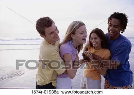 Stock Image - Two teenage couples holding each other at the beach. Fotosearch