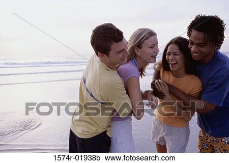 Stock Image - Two teenage couples holding each other at the beach. Fotosearch