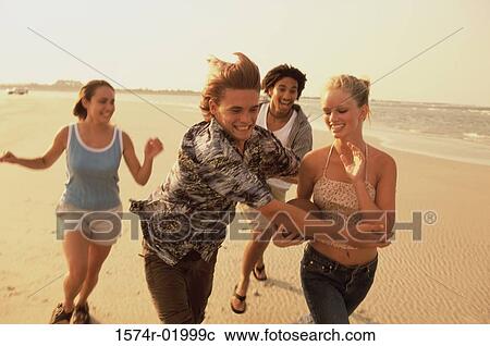 Stock Image - Two teenage couples playing football on the beach. Fotosearch