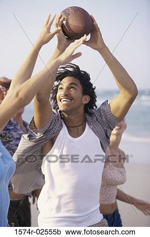 Stock Image - Two teenage couples playing football on the beach. Fotosearch